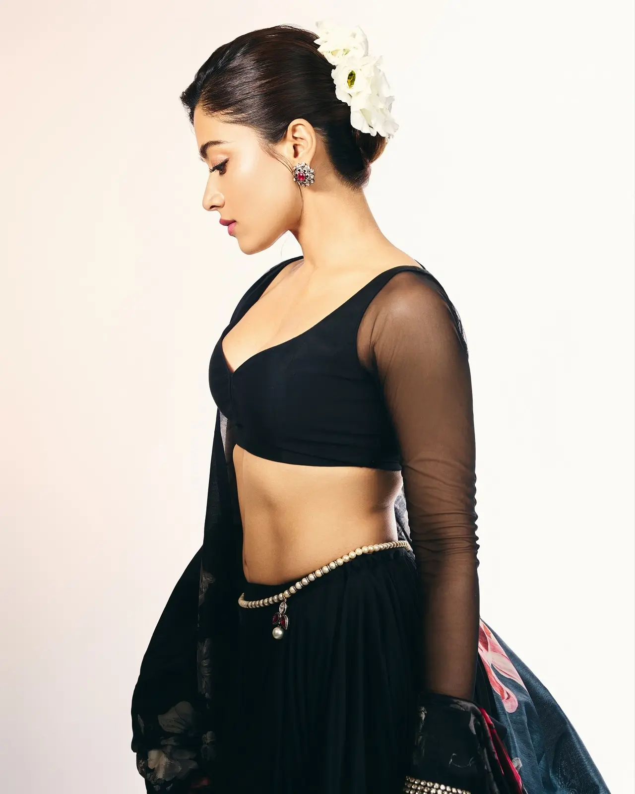 She styled it with a delicate kamarbandh that accentuates her waist, while statement earrings and bangles complete the look. Her hair is styled in a sleek bun adorned with white flowers.